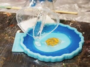 El proceso artístico de verter resina epoxi en un juguete dorado. proceso tecnológico de creación de una pintura en arte de resina de estilo